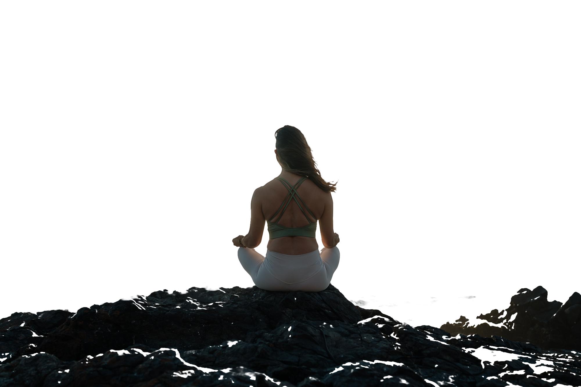 Daniela Díaz meditando en las rocas frente al mar